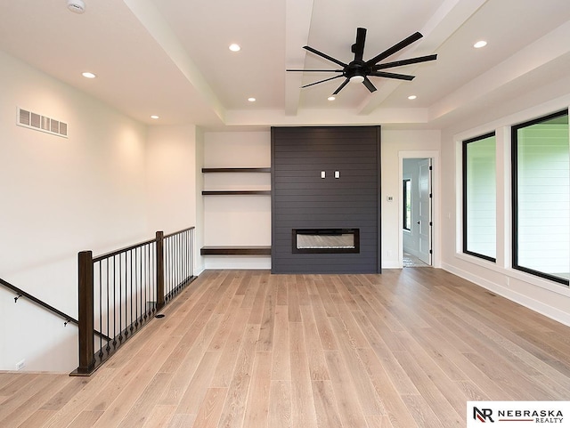 unfurnished living room with recessed lighting, a large fireplace, visible vents, light wood finished floors, and beamed ceiling