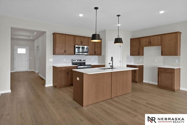 kitchen with stainless steel appliances, brown cabinetry, a sink, and light wood finished floors