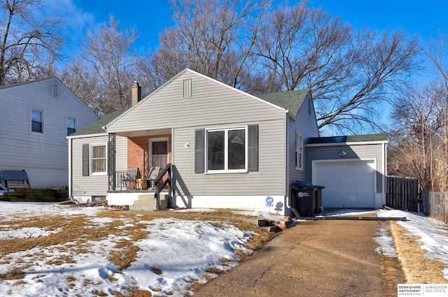 view of front of home with a garage, a chimney, fence, and aphalt driveway