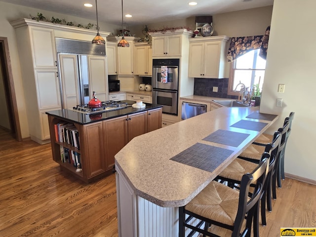 kitchen featuring stainless steel appliances, light wood-style floors, a sink, and a kitchen breakfast bar