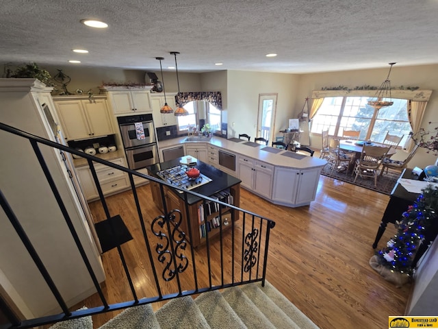 kitchen with light wood-style floors, stainless steel appliances, plenty of natural light, and a peninsula