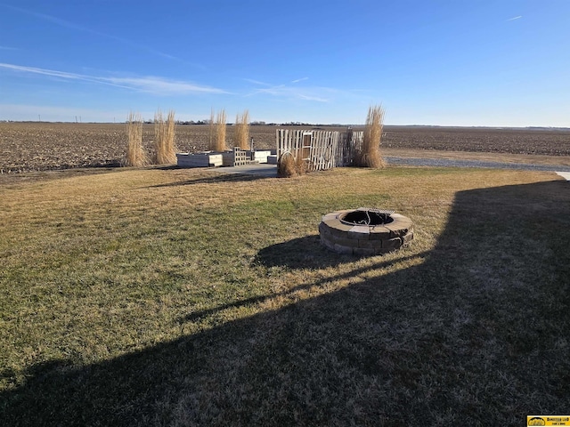 view of yard with an outdoor fire pit and a rural view