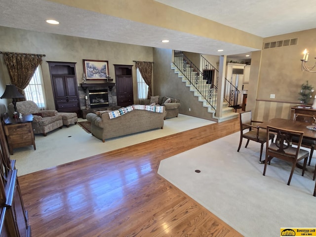 living room with recessed lighting, wood finished floors, visible vents, stairs, and a glass covered fireplace