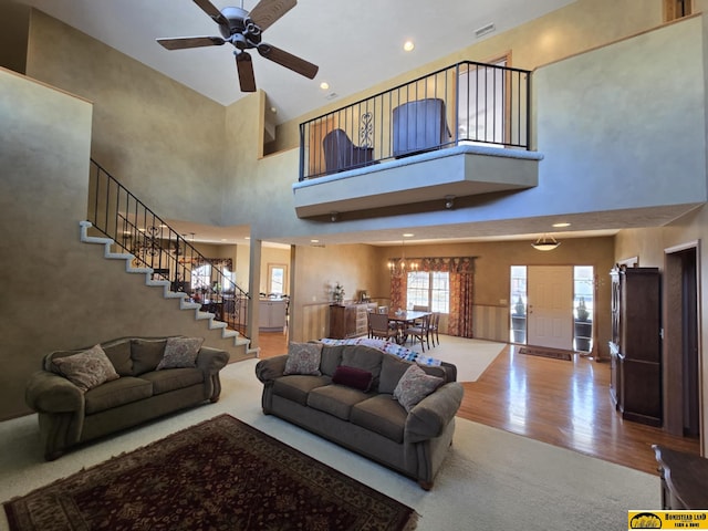 living area featuring a ceiling fan, stairway, wood finished floors, a high ceiling, and recessed lighting