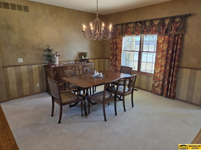 carpeted dining area with baseboards, visible vents, and an inviting chandelier