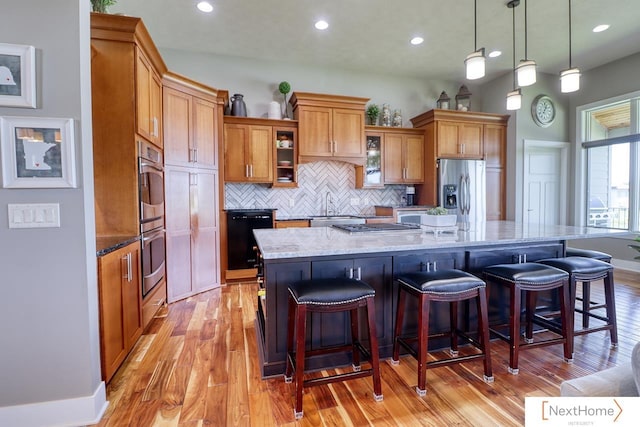 kitchen featuring brown cabinetry, a large island, stainless steel appliances, and a kitchen breakfast bar