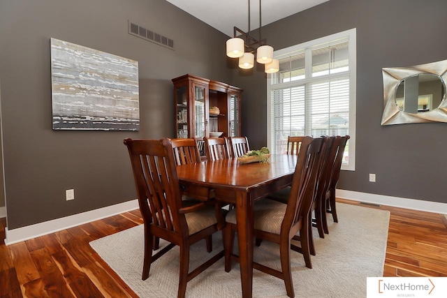 dining room with an inviting chandelier, baseboards, visible vents, and wood finished floors