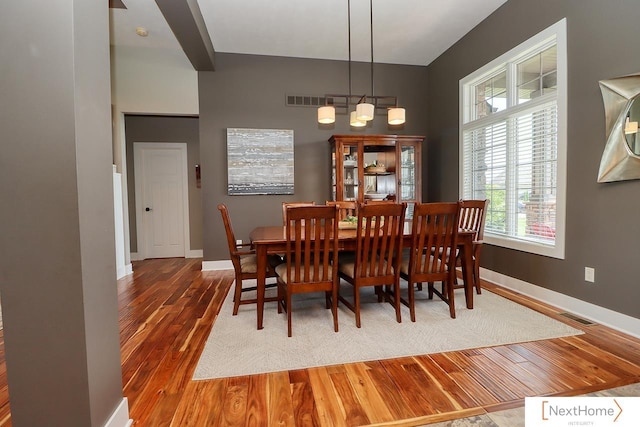 dining area with wood finished floors, visible vents, and baseboards