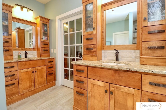 bathroom with tasteful backsplash, two vanities, a sink, and wood finished floors