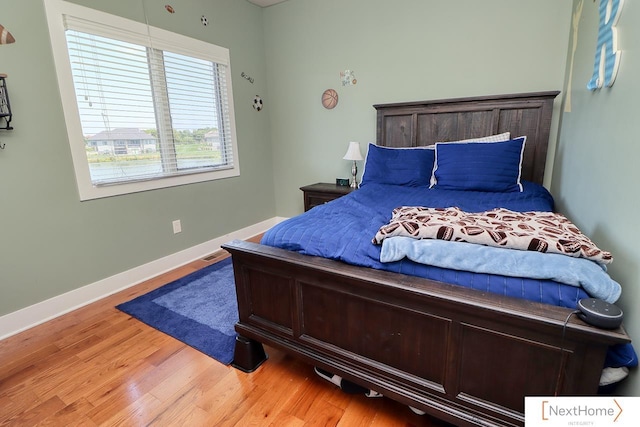 bedroom featuring wood finished floors, visible vents, and baseboards