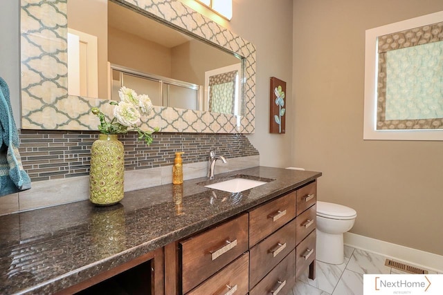 bathroom featuring marble finish floor, decorative backsplash, a stall shower, vanity, and baseboards