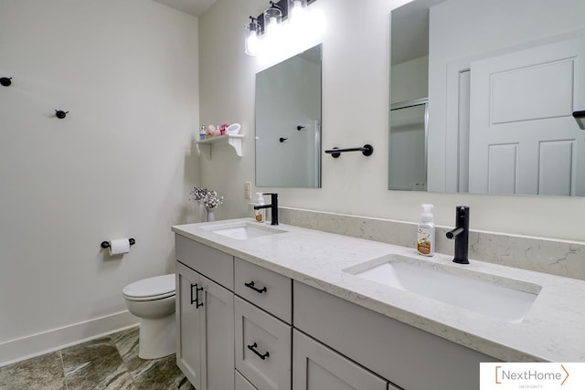 full bath featuring toilet, double vanity, baseboards, and a sink