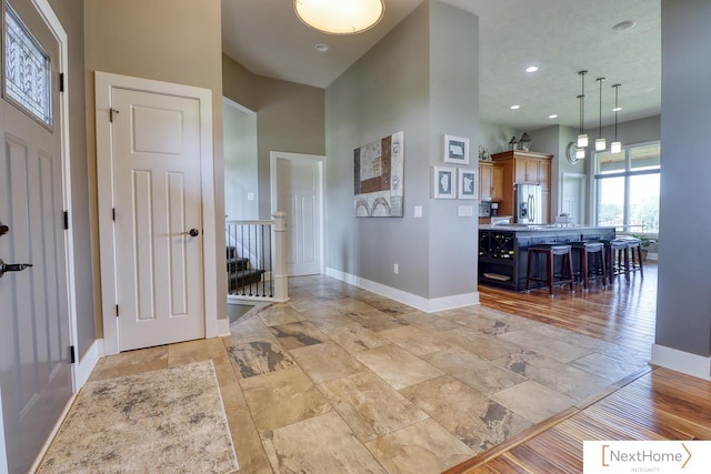 entrance foyer featuring recessed lighting, a towering ceiling, and baseboards