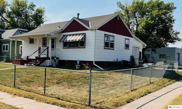 bungalow with a front lawn, a fenced front yard, and a shingled roof