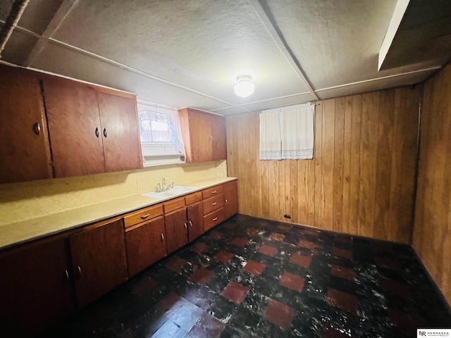 kitchen featuring light countertops, a sink, and wooden walls