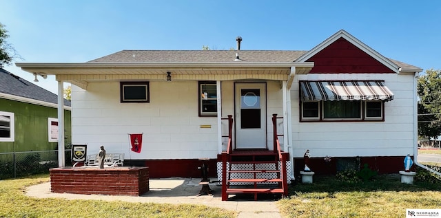 bungalow with entry steps, roof with shingles, and fence