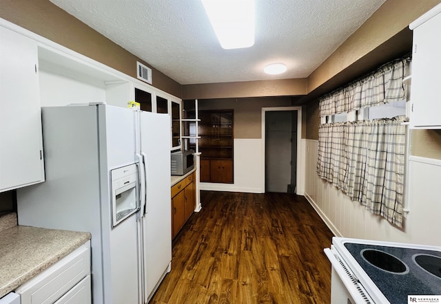 kitchen featuring white appliances, a wainscoted wall, dark wood-type flooring, light countertops, and a textured ceiling