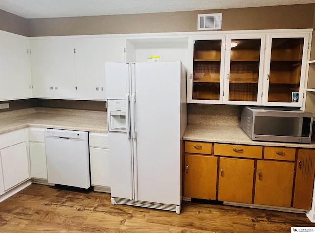 kitchen featuring white appliances, visible vents, light countertops, light wood finished floors, and brown cabinetry