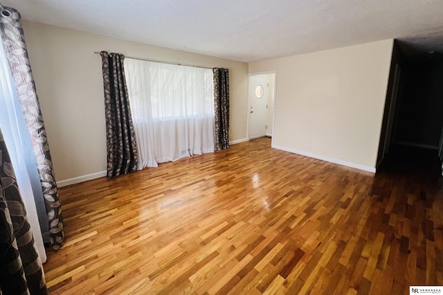 spare room featuring wood finished floors and baseboards