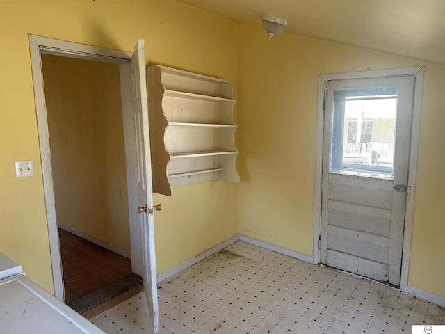 entryway with lofted ceiling, light floors, and baseboards