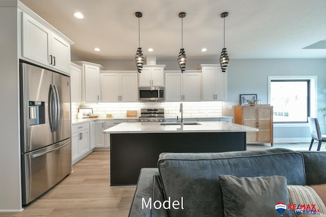 kitchen with light wood finished floors, appliances with stainless steel finishes, backsplash, and a sink