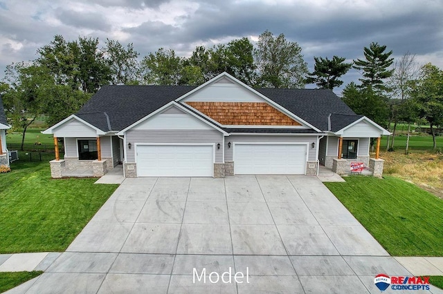 craftsman-style house featuring covered porch, concrete driveway, a garage, stone siding, and a front lawn