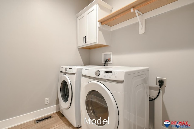 laundry room with visible vents, baseboards, cabinet space, light wood finished floors, and washer and clothes dryer