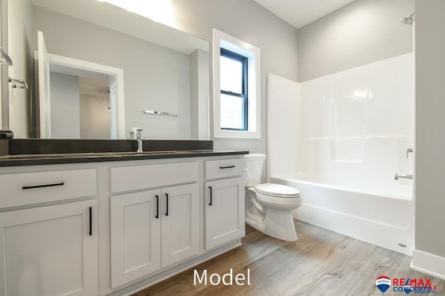 bathroom featuring  shower combination, vanity, toilet, and wood finished floors