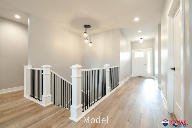 corridor with recessed lighting, baseboards, wood finished floors, and an upstairs landing