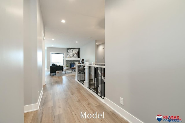 hall featuring light wood finished floors, recessed lighting, and baseboards