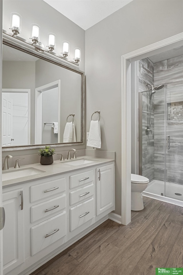 bathroom with a sink, a shower stall, toilet, and wood finished floors