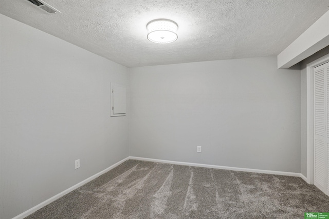 empty room featuring a textured ceiling, carpet floors, visible vents, and baseboards