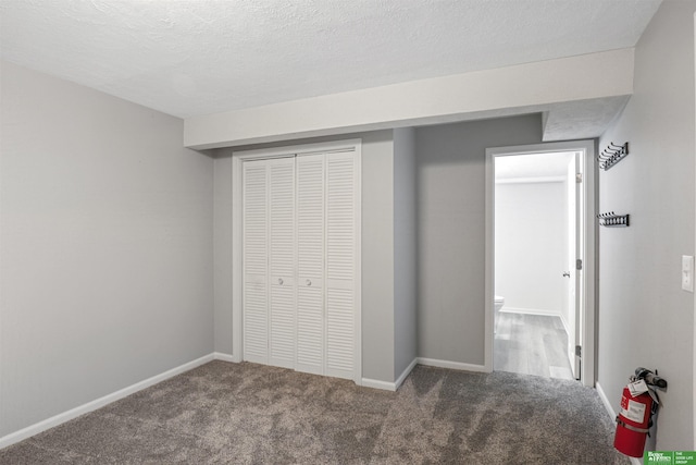 unfurnished bedroom with carpet floors, a closet, a textured ceiling, and baseboards