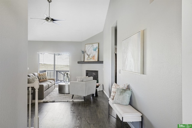 living area with dark wood-style floors, high vaulted ceiling, a glass covered fireplace, and a ceiling fan