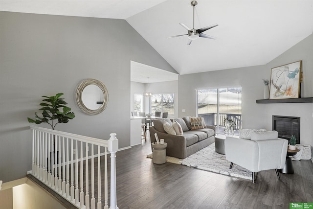 living room with a glass covered fireplace, ceiling fan, wood finished floors, high vaulted ceiling, and baseboards