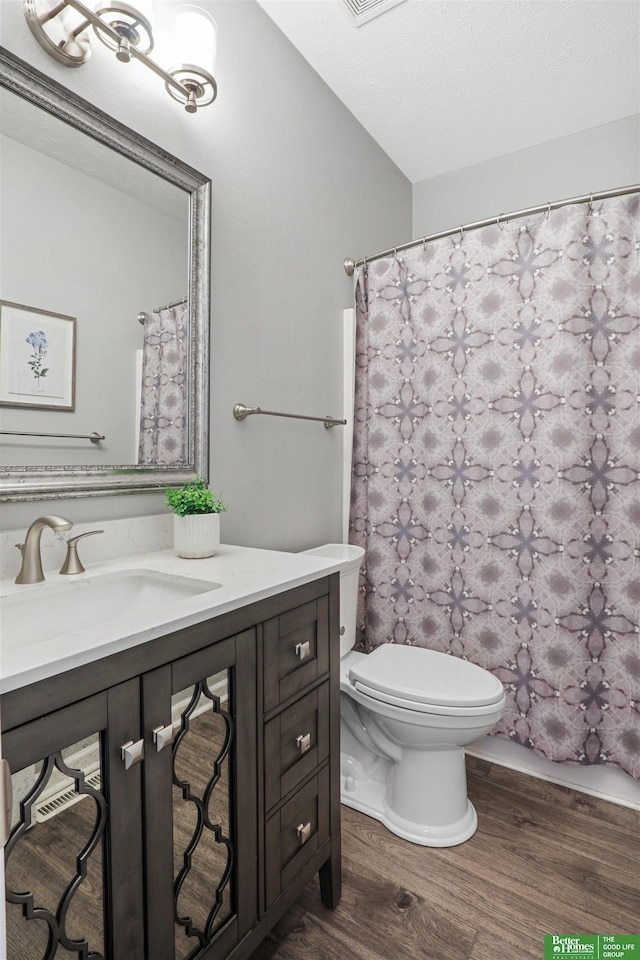 bathroom with toilet, a shower with shower curtain, wood finished floors, and vanity