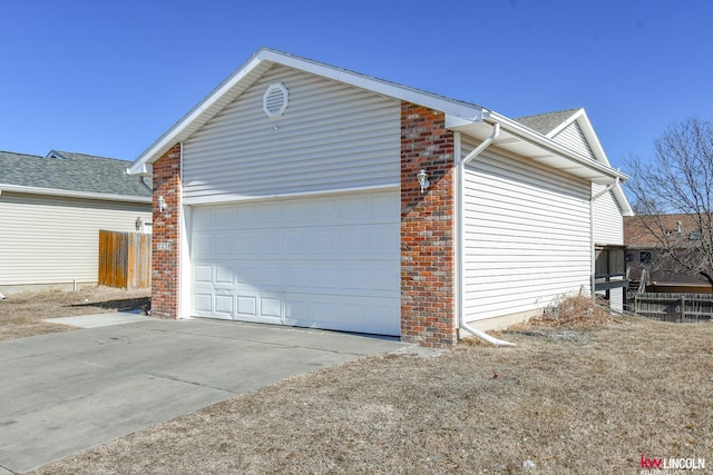 view of home's exterior with an attached garage, fence, concrete driveway, and brick siding