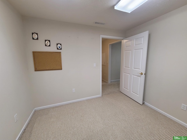 unfurnished room with light carpet, visible vents, and baseboards