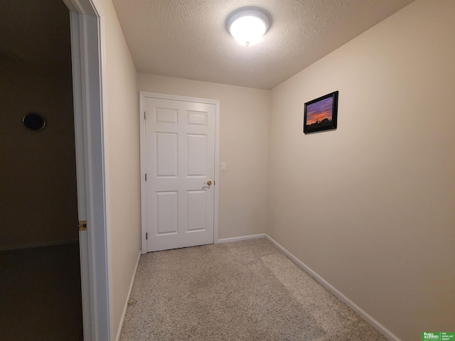 hall featuring carpet, baseboards, and a textured ceiling