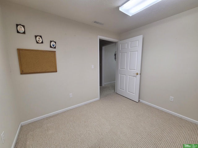 spare room with baseboards, visible vents, and light colored carpet