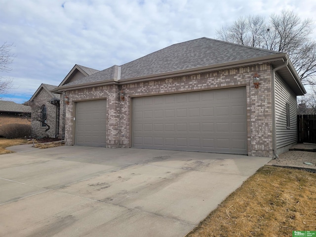 view of front of property with a garage, a shingled roof, concrete driveway, and brick siding