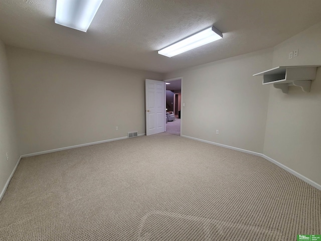 empty room featuring baseboards, a textured ceiling, visible vents, and light colored carpet