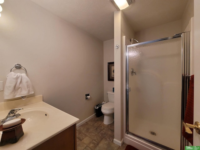 bathroom featuring a stall shower, vanity, toilet, and baseboards