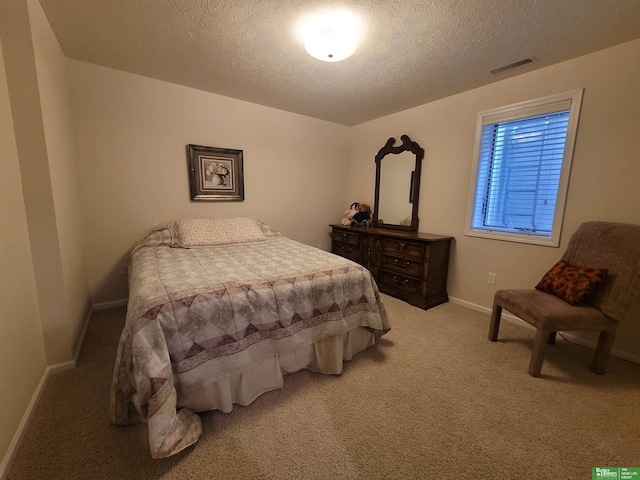 bedroom featuring a textured ceiling, carpet flooring, visible vents, and baseboards