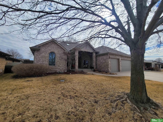 ranch-style home with an attached garage, concrete driveway, brick siding, and a front yard