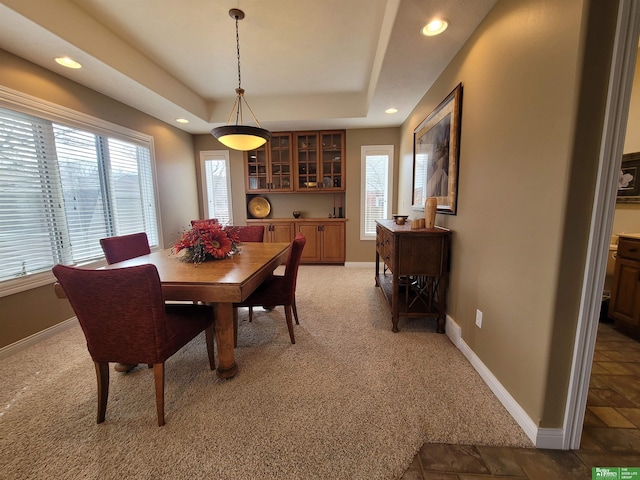 dining room featuring light carpet, recessed lighting, a raised ceiling, and baseboards