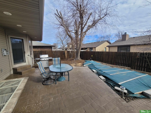 view of patio featuring entry steps, outdoor dining space, a fenced backyard, and a grill