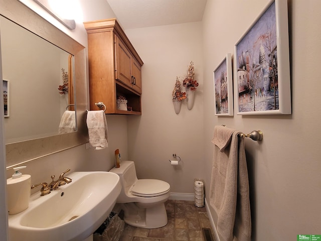 bathroom with toilet, visible vents, baseboards, and a sink