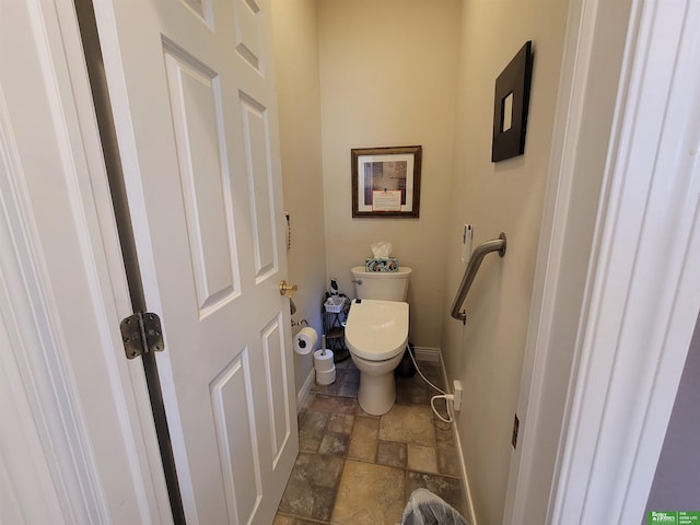 bathroom with baseboards, toilet, and stone tile floors