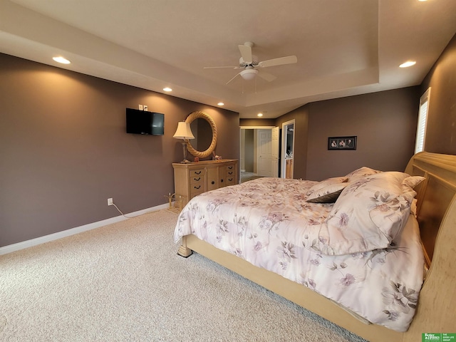 carpeted bedroom with recessed lighting, a raised ceiling, and baseboards